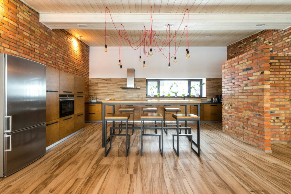 Spacious kitchen interior with industrial design, featuring brick walls and wooden accents.